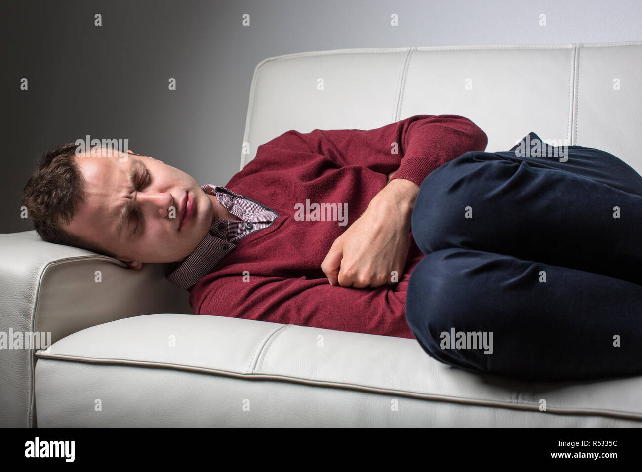 Giovane uomo che soffre di gravi dolori di pancia, di essere monopolizzati dalla condizione debilitante della malattia celiaca/morbo di Crohn Foto Stock