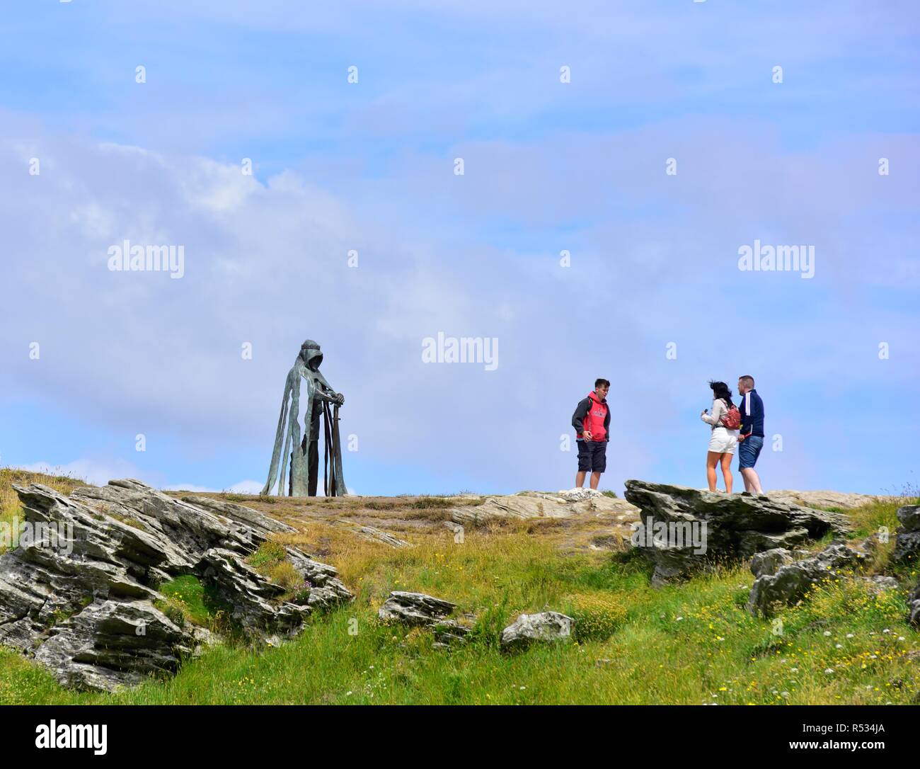 I turisti in piedi accanto al Re Artù un 8 ft scultura in bronzo di artista Rubin Eynon, denominato Gallos Cornish word per potenza, Tintagel Castle,cornwall, Regno Unito Foto Stock
