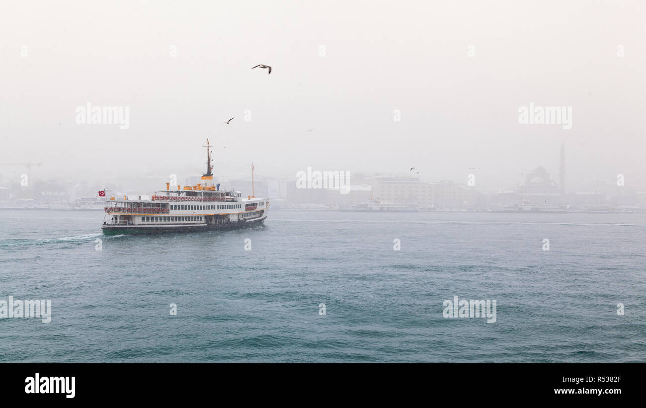 Inverno e nevicate in Istanbul, sul Bosforo navi passeggeri, sfondo quartiere Eminonu Foto Stock
