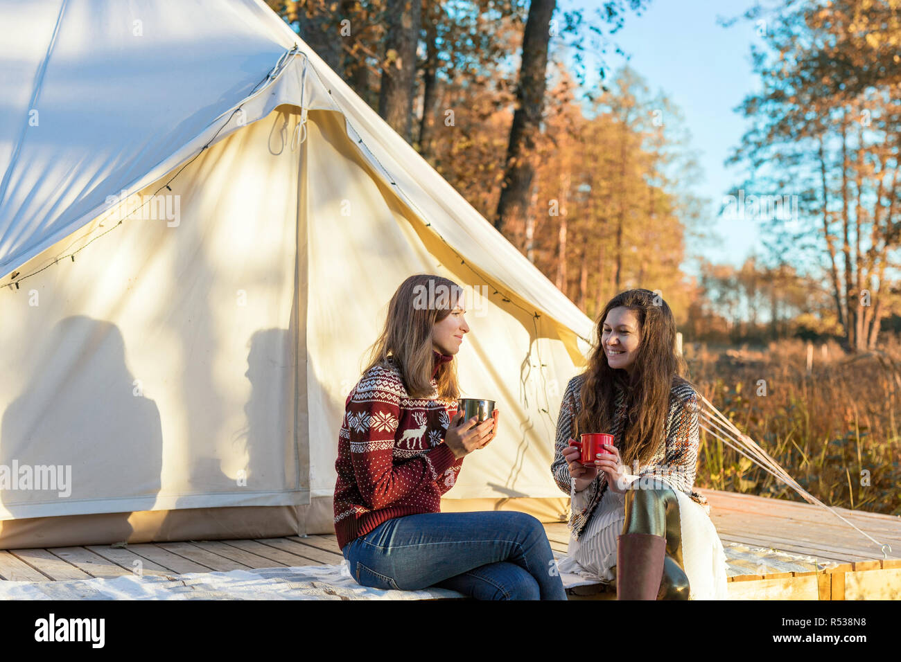 Due amici felice di bere il caffè durante i momenti di relax nei pressi di tela tenda a campana Foto Stock