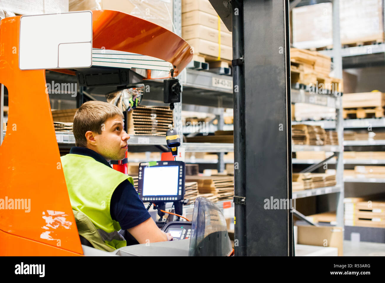 Giovane uomo in abiti da lavoro, driver Reachtruck occupato a lavorare sulla logistica magazzino store Foto Stock