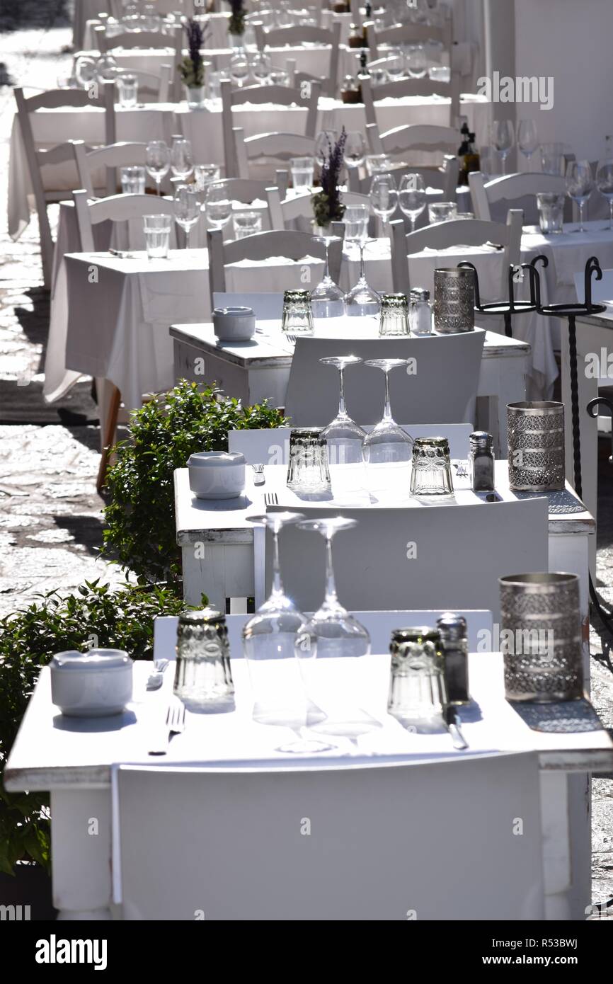 Tavoli finemente insieme,tutto in bianco su ciottoli con passi - ristorante con terrazza all'aperto in climi soleggiati Foto Stock