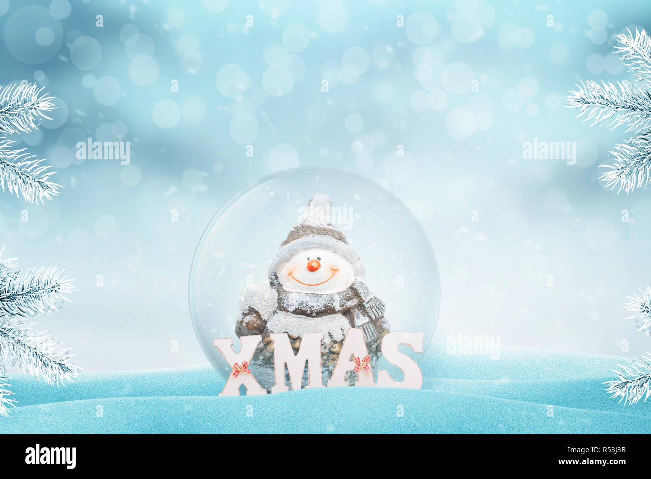 Crystal magic ball con un pupazzo di neve. XMAS lettere accanto a. Copia spazio sopra. Luce e bokeh in background. Foto Stock
