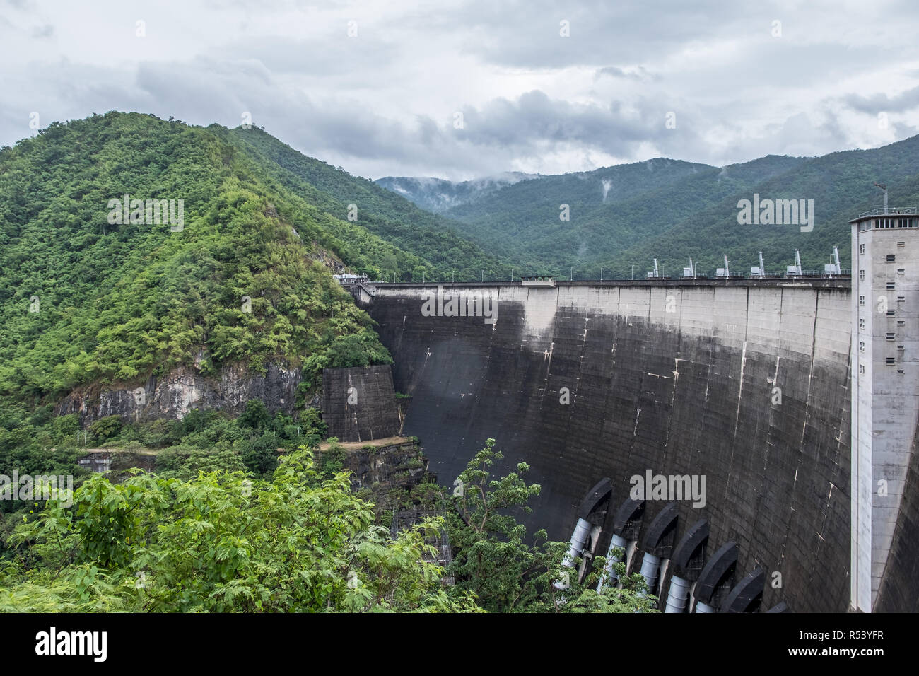 Arco grande diga in calcestruzzo con il tubo di acqua per idroelettrico generatore nella valle del nord della Thailandia. Foto Stock