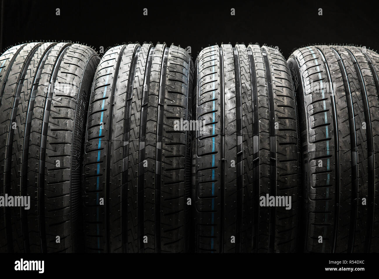 Pila di nuovo di zecca pneumatici vettura ad alte prestazioni su pulire basso-chiave nero di sfondo per studio Foto Stock