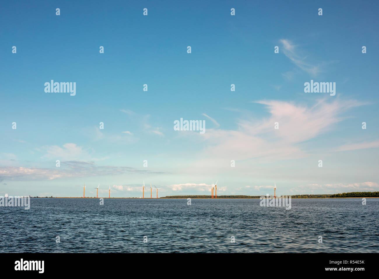 Colorata, arancione e rosso, mulini a vento in Almere Pampus, 10 windturbines in un cluster, visto dal markermeer, all'orizzonte. Foto Stock