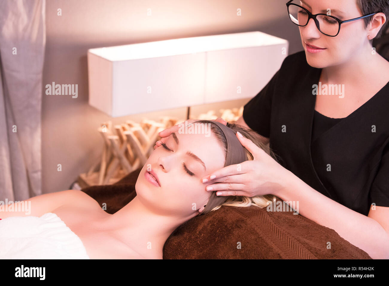 Massaggiatrice Massaggiare le tempie di una giovane donna Foto stock - Alamy
