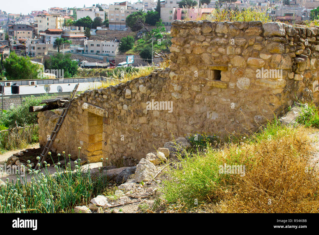 Uno stile retrò casa di pietra in open air museum di Nazareth Village Israele. case nella moderna Nazaret può essere visto in background. Questo sito gi Foto Stock