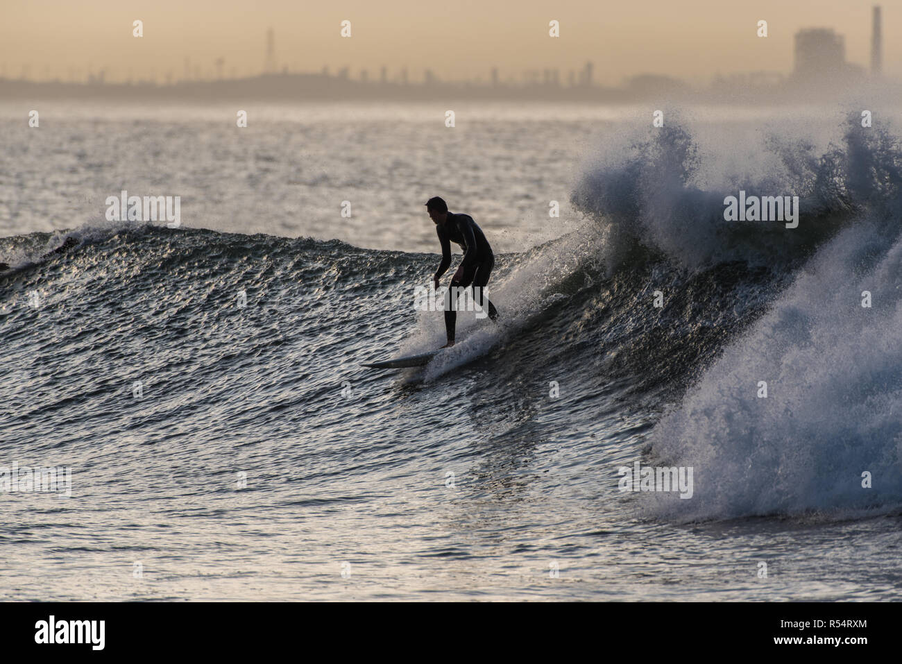 Surfer silhouette in classic la postura come egli scende in una serie in onda Ventura, California, Stati Uniti d'America durante il tardo autunno si rigonfiano il 28 novembre 2018. Foto Stock