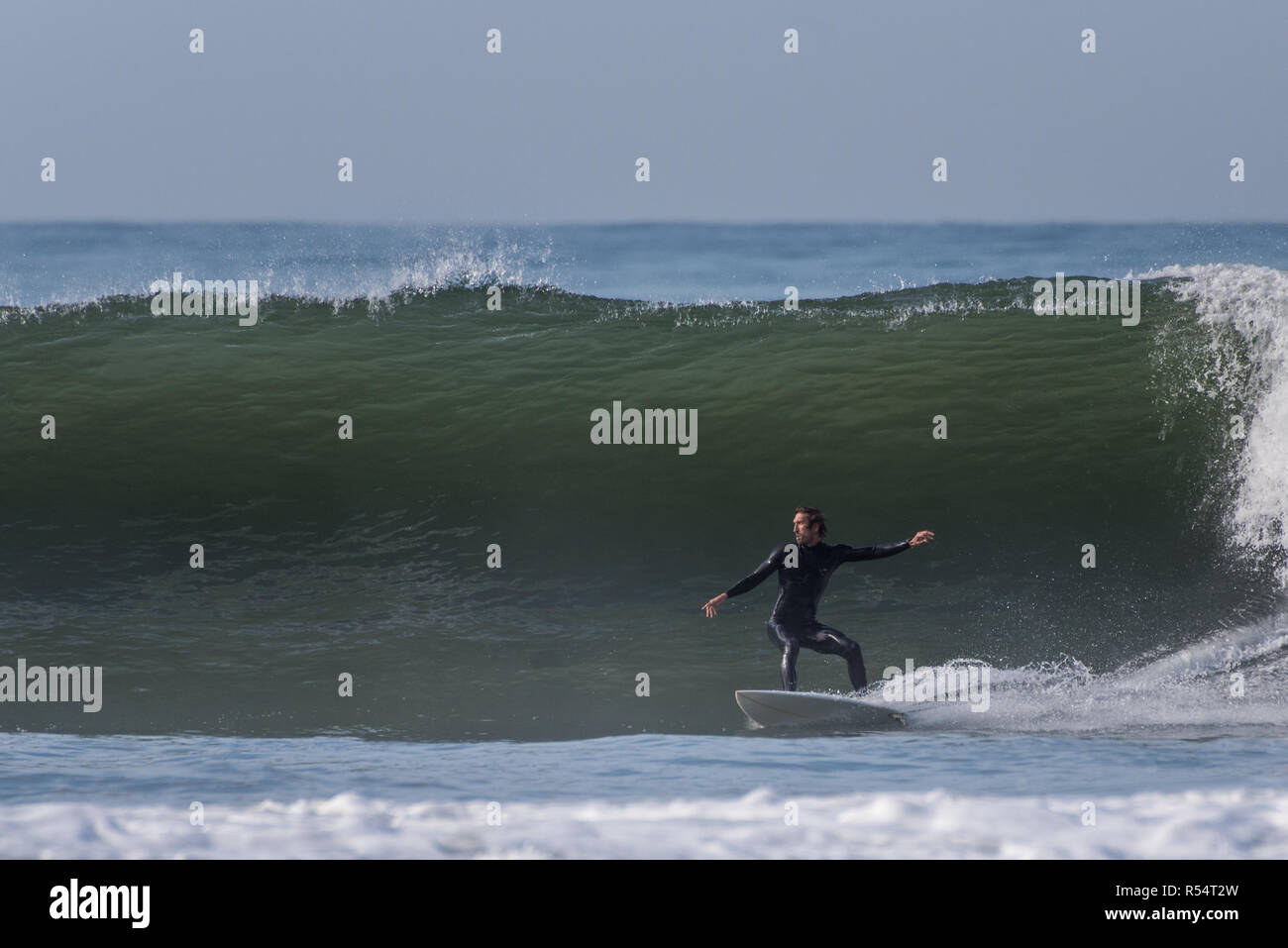 Surfer con le braccia distese per equilibrio come egli scende in una grande ondata di Ventura, California, Stati Uniti d'America durante il tardo autunno si rigonfiano il 28 novembre 2018. Foto Stock