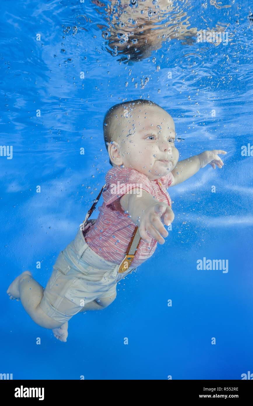 Little Boy in una tuta con bretelle nuotare sott'acqua su un blu sullo  sfondo dell'acqua. Un sano stile di vita di famiglia e bambini acqua  attività sportive. Bambino d Foto stock -