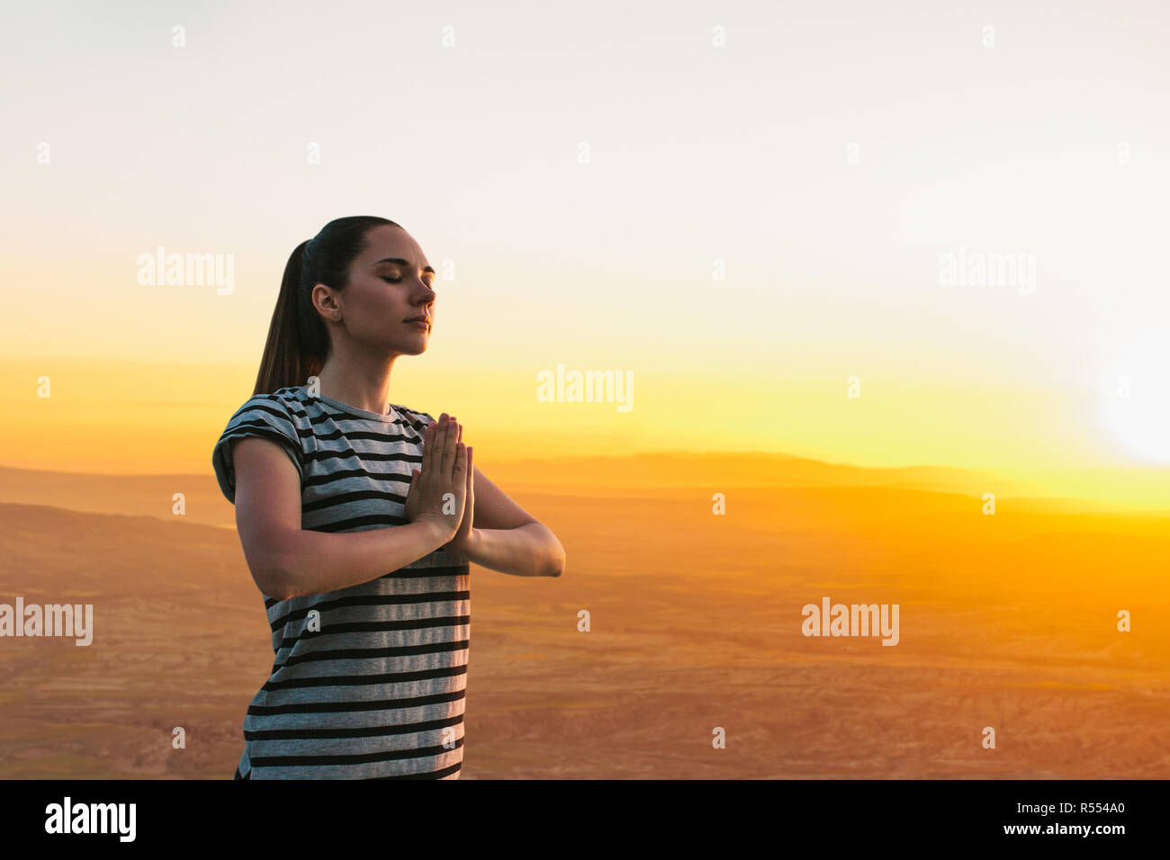 Una ragazza le pratiche yoga o la meditazione o la ricerca di un'anima contro lo sfondo di un bel tramonto. Solitudine e scollegato Foto Stock