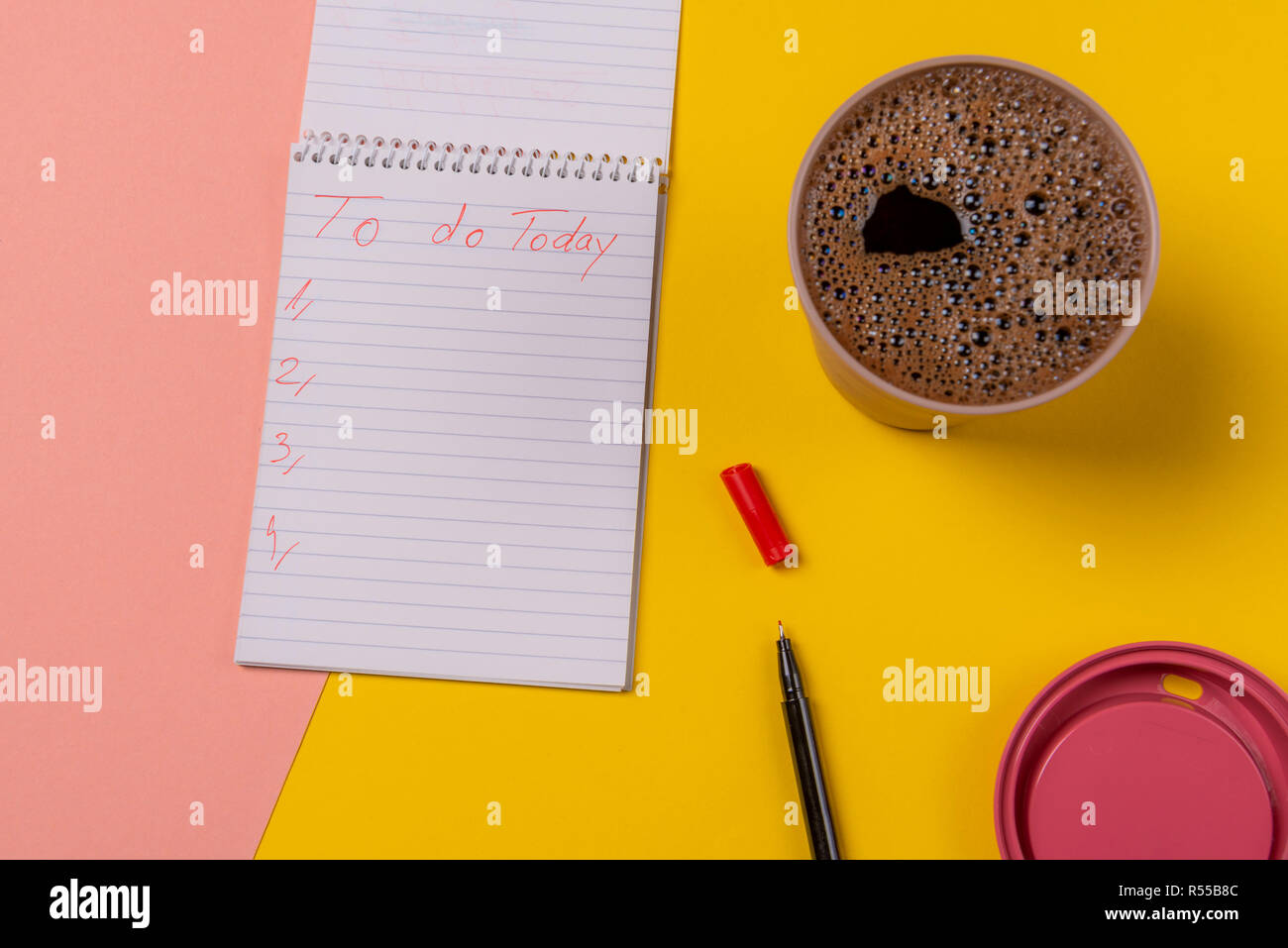 Tazza di caffè caldo e una spirale aperta notebook con i piani di oggi elenco. Vista sopra con un colorato scrivania Foto Stock