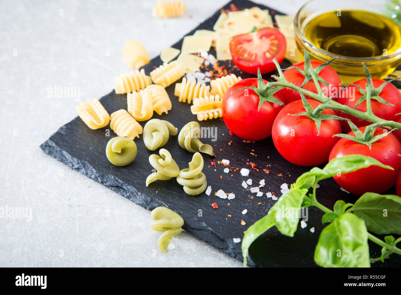 Ingredienti per la pasta. Pomodori ciliegini, pasta di basilico fresco, spezie su uno sfondo di pietra, closeup, il fuoco selettivo Foto Stock