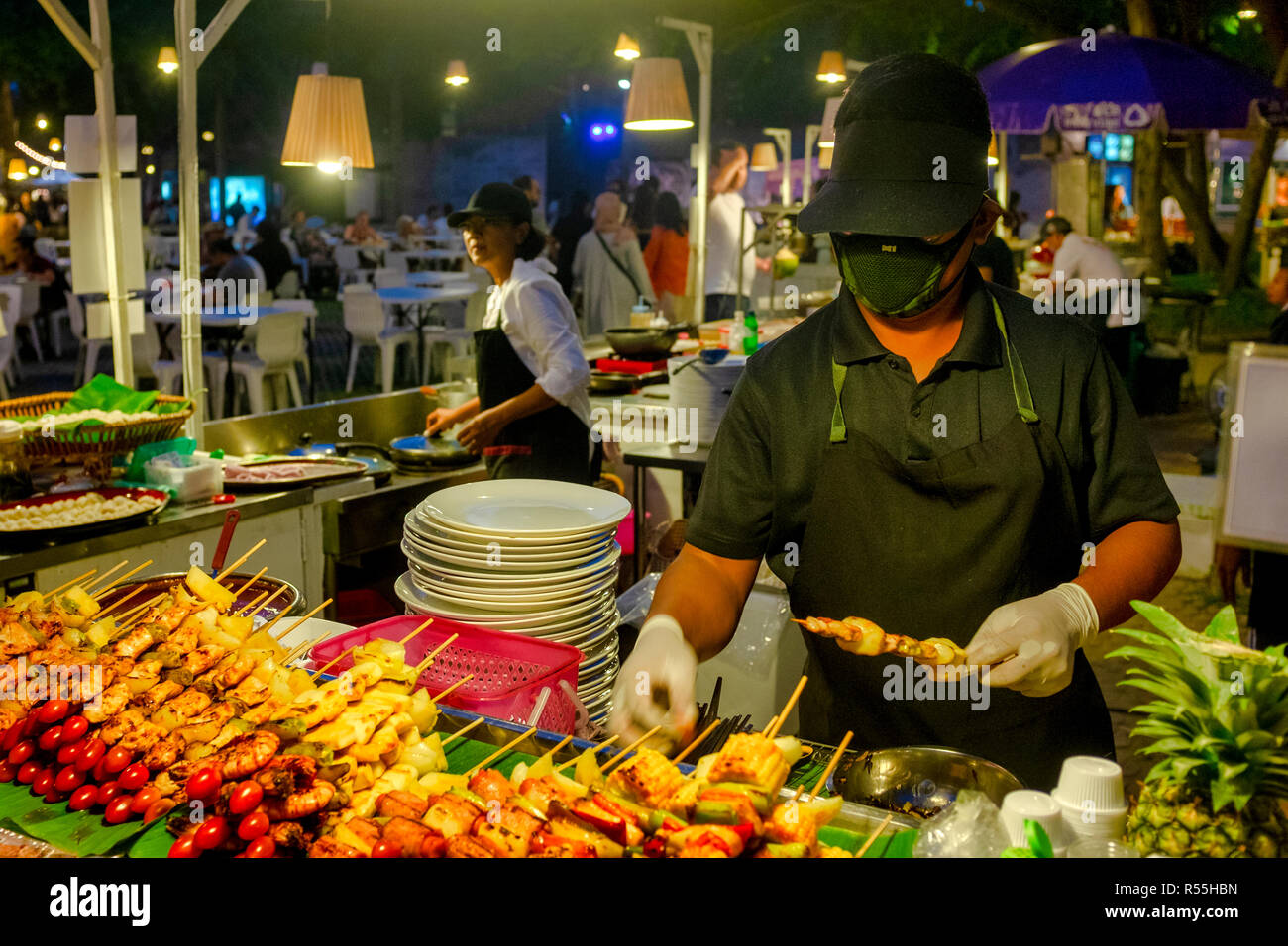 Stand alimentari venditore la preparazione di spiedini di carne in la cicala mercato del weekend, Hua Hin, Thailandia Foto Stock