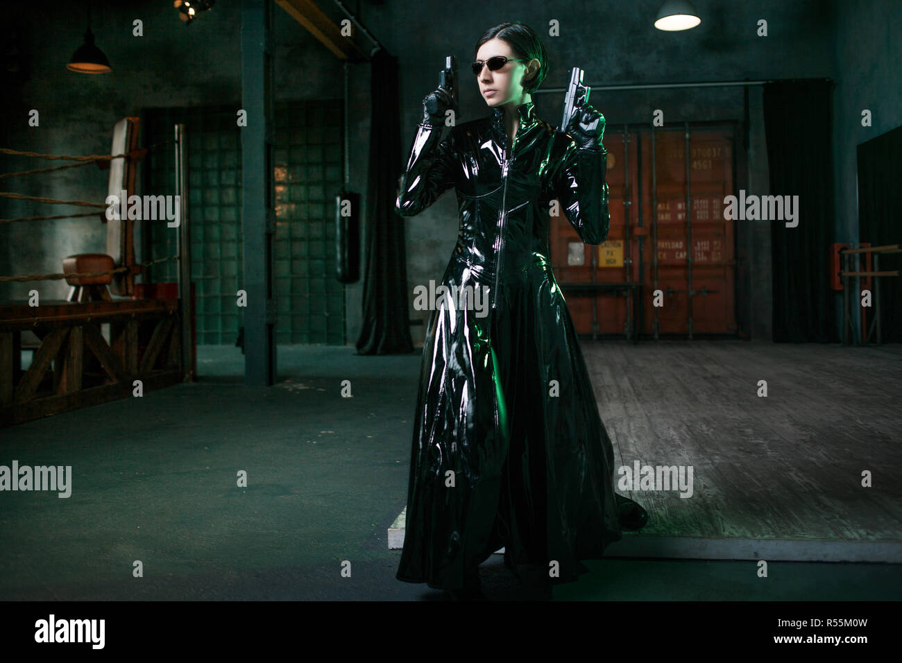Virus e sicurezza informatica, concetto. giovane donna vestita in stile Matrix. Ragazza hacker in cuoio nero con le pistole. Foto Stock
