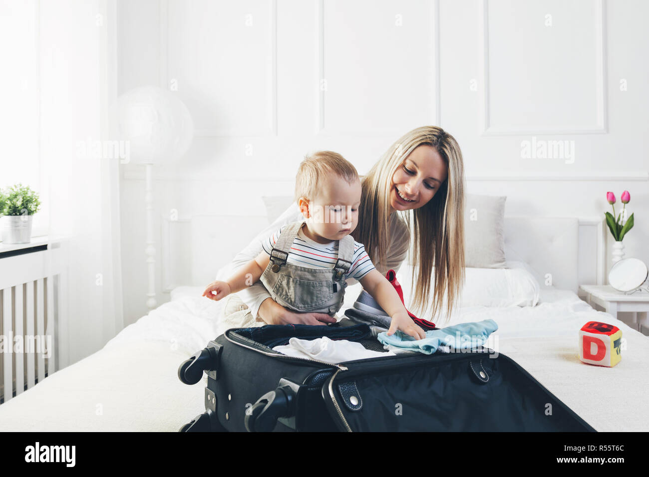 Viaggiare con i bambini. Felice madre con il suo bambino abiti di imballaggio per le vacanze Foto Stock