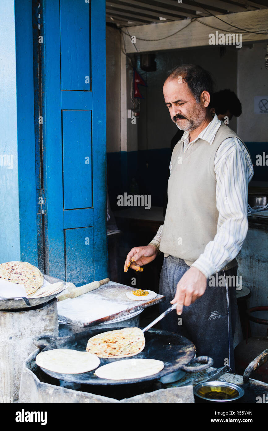 KATHMANDU, NEPAL - Aprile 2015: street cook roti di cottura del pane nel suo open street shop. Orientamento verticale. Foto Stock