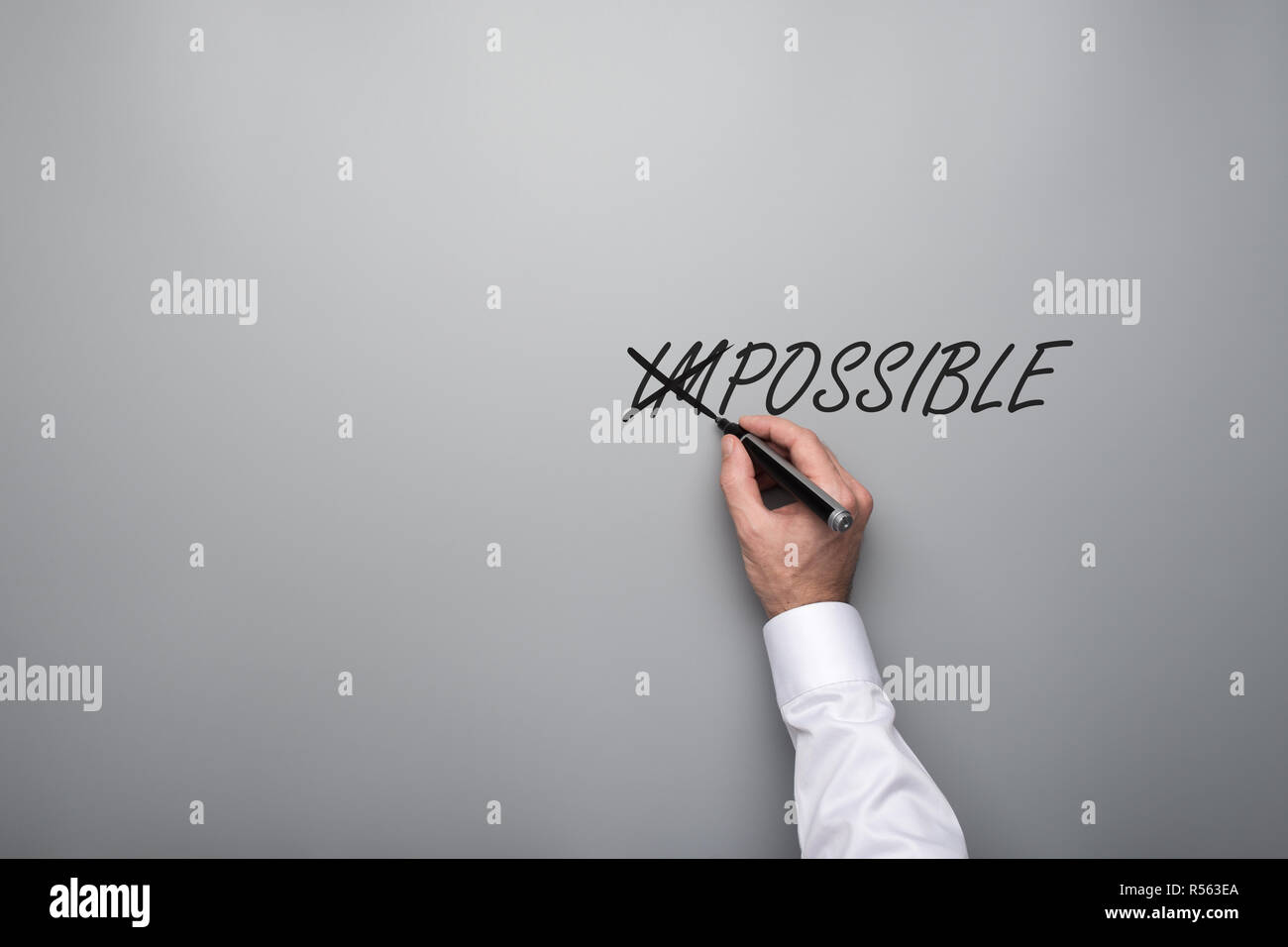 Maschio incrocio mano off lettere IM nel termine impossibile scritto su uno sfondo grigio con abbondanza di spazio di copia. Foto Stock