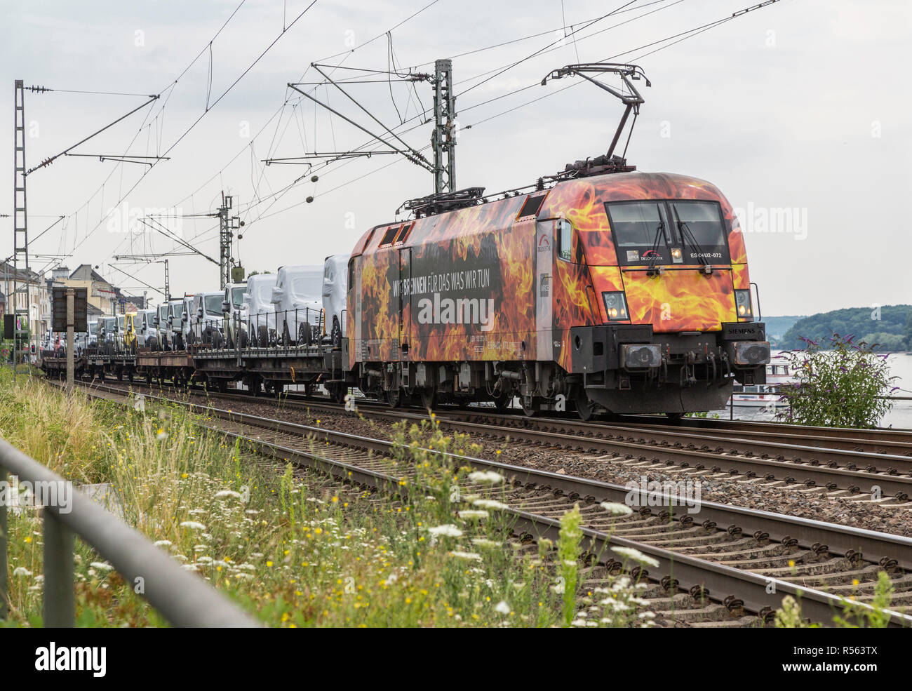 Rudesheim, Hesse, Germania. Locomotiva elettrica portando nuovo Automotive furgoni al mercato. Foto Stock