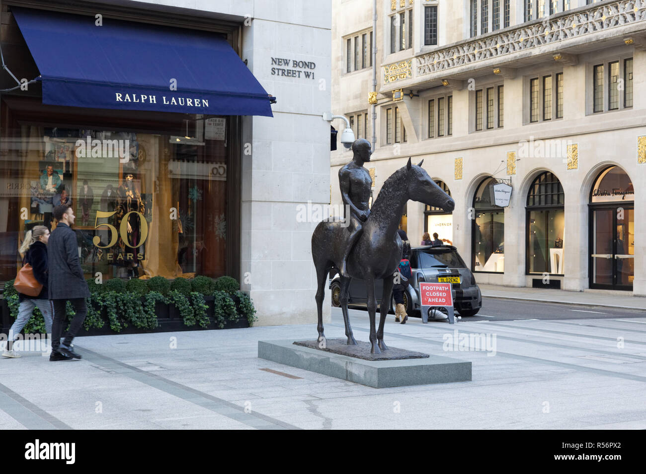 Giovane oltrepassando Ralph Lauren e una statua equestre su New Bond Street Londra Foto Stock