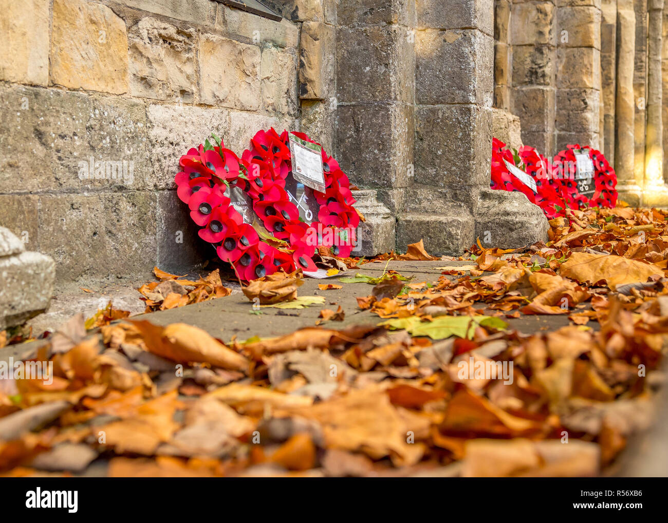 Ghirlande di ricordo contro un muro monumentale con foglie di autunno. Foto Stock