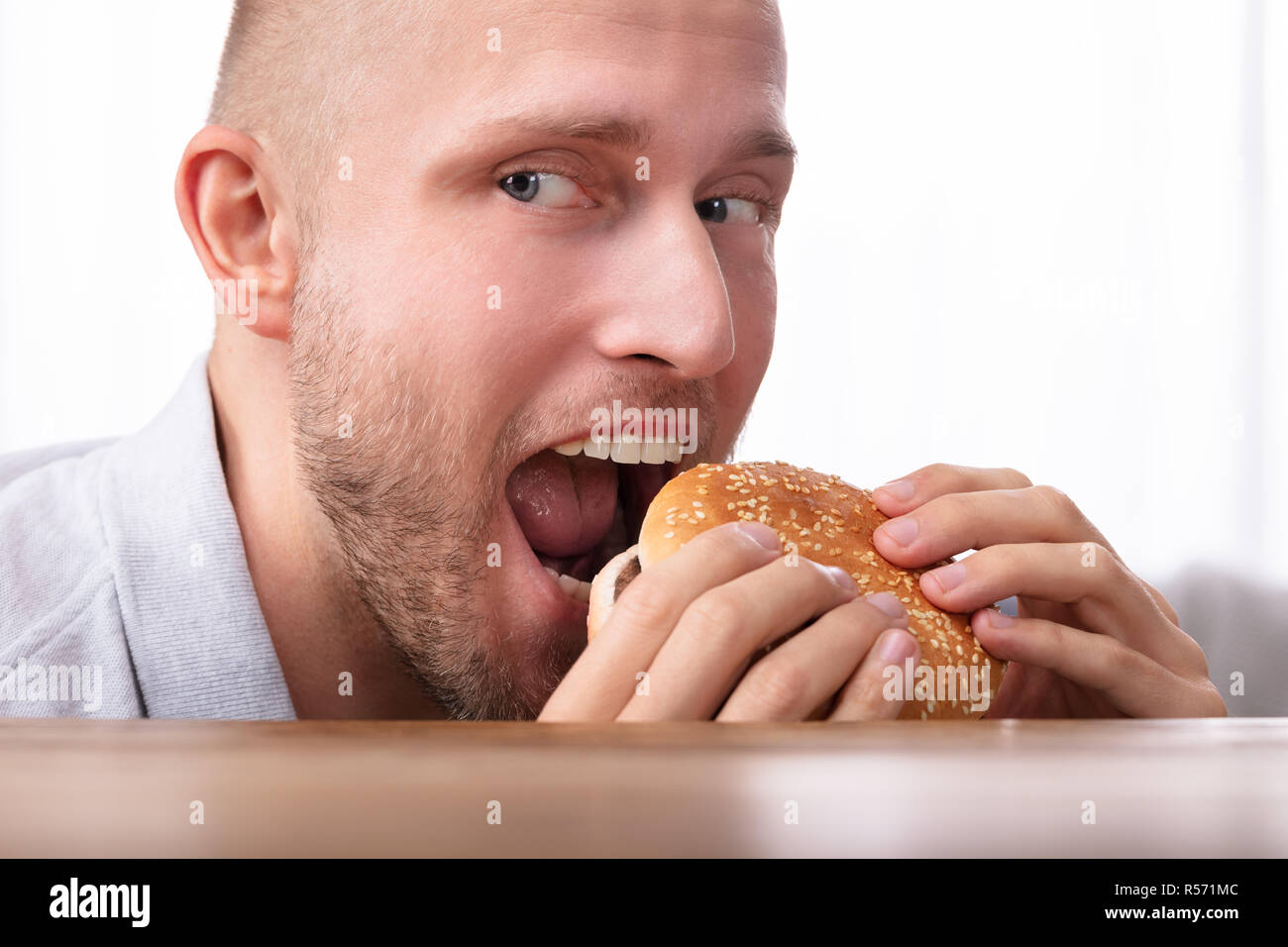 Ritratto di un avido giovane mangiare hamburger Foto Stock