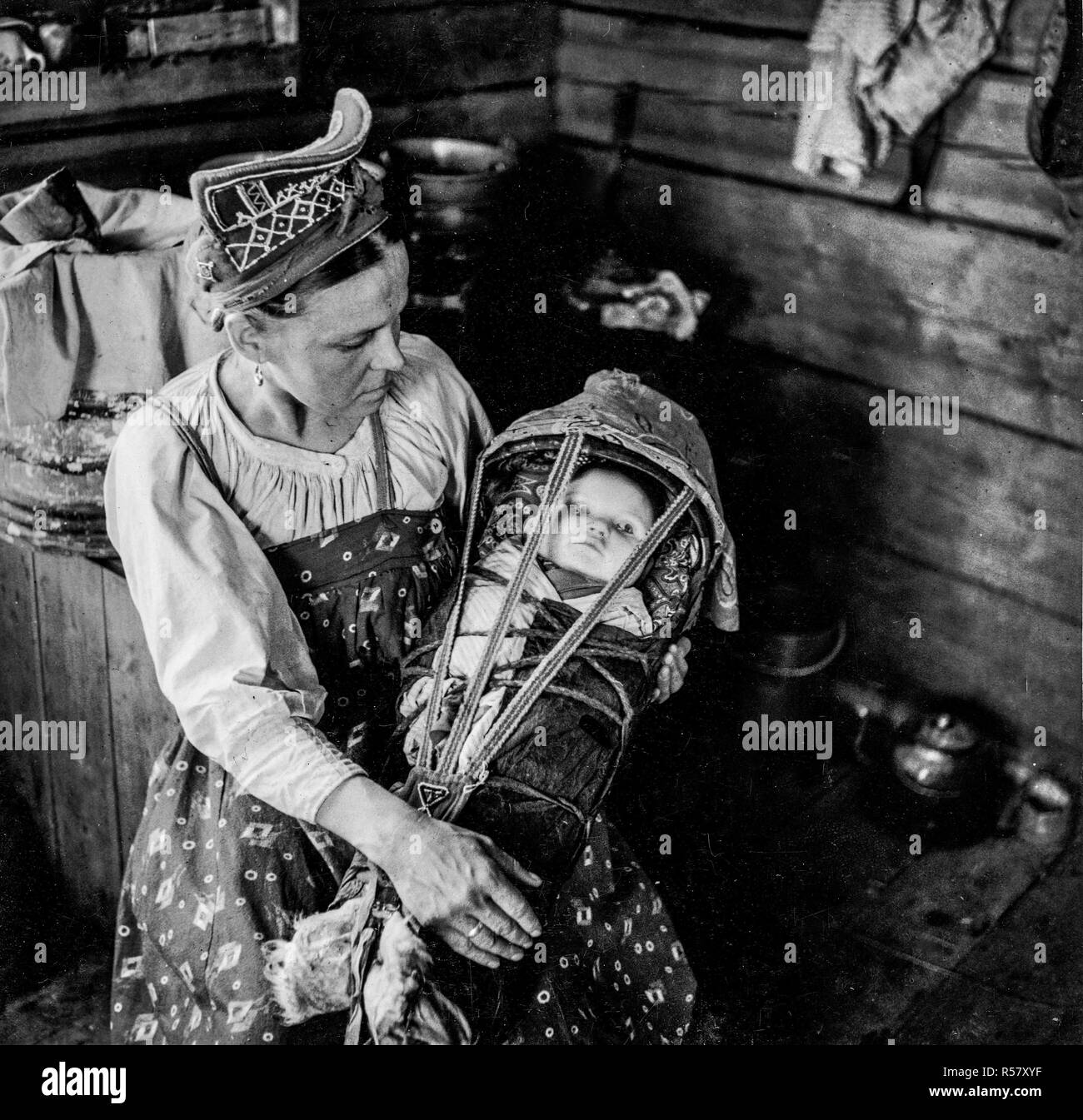 Villaggio d'inverno. Sami Skolt donna e bambino. La madre indossa una perla ricamato 'shamtshik'. Foto Stock