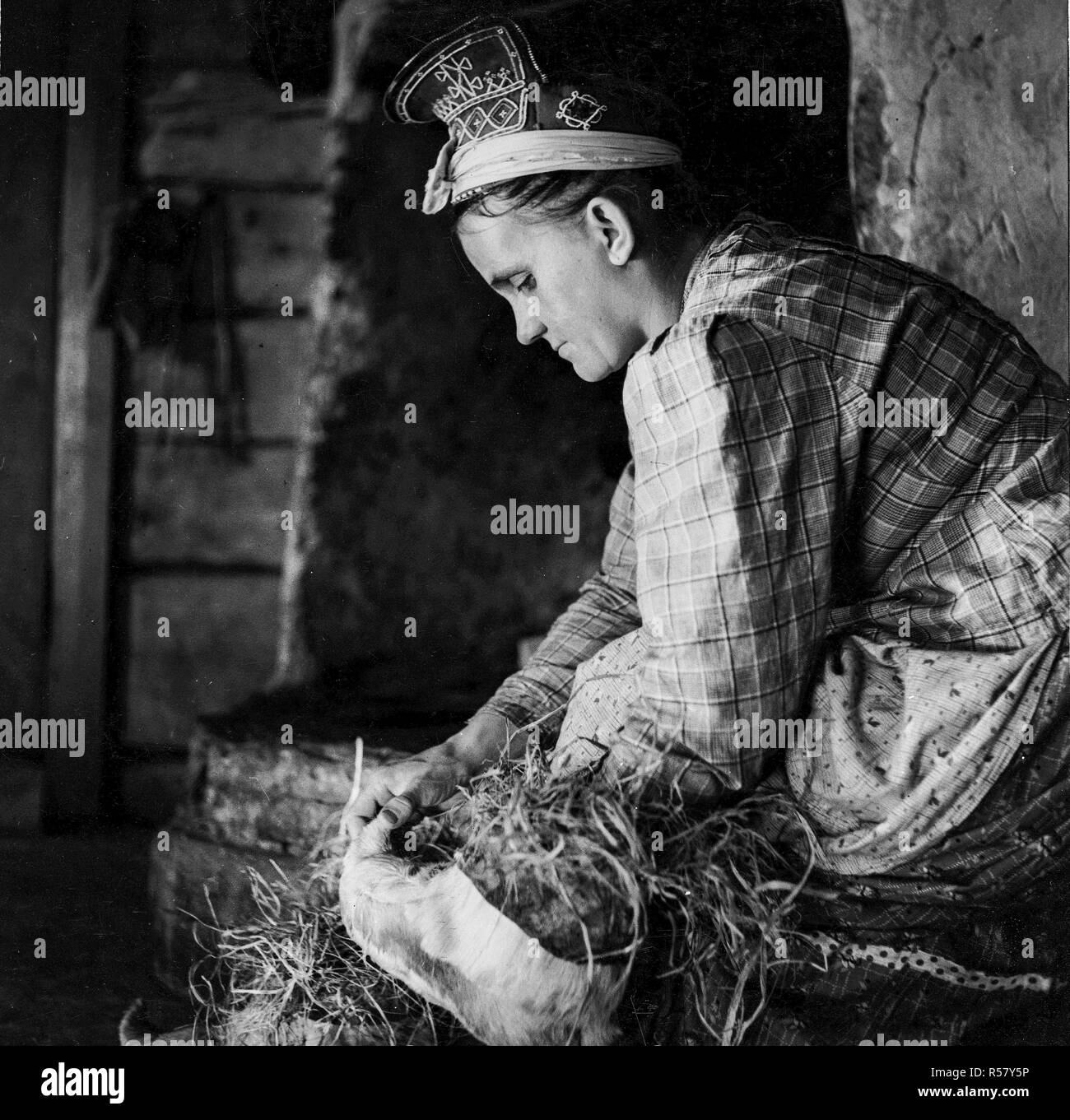 Finlandia - Storia - ca. 1938 - villaggio d'inverno. Ogni mattina il Sami Skolt moglie si riempie di suo marito "nutukka' scarpe con fieno morbido. Suenjel (Suonikylä), Petsamo Foto Stock