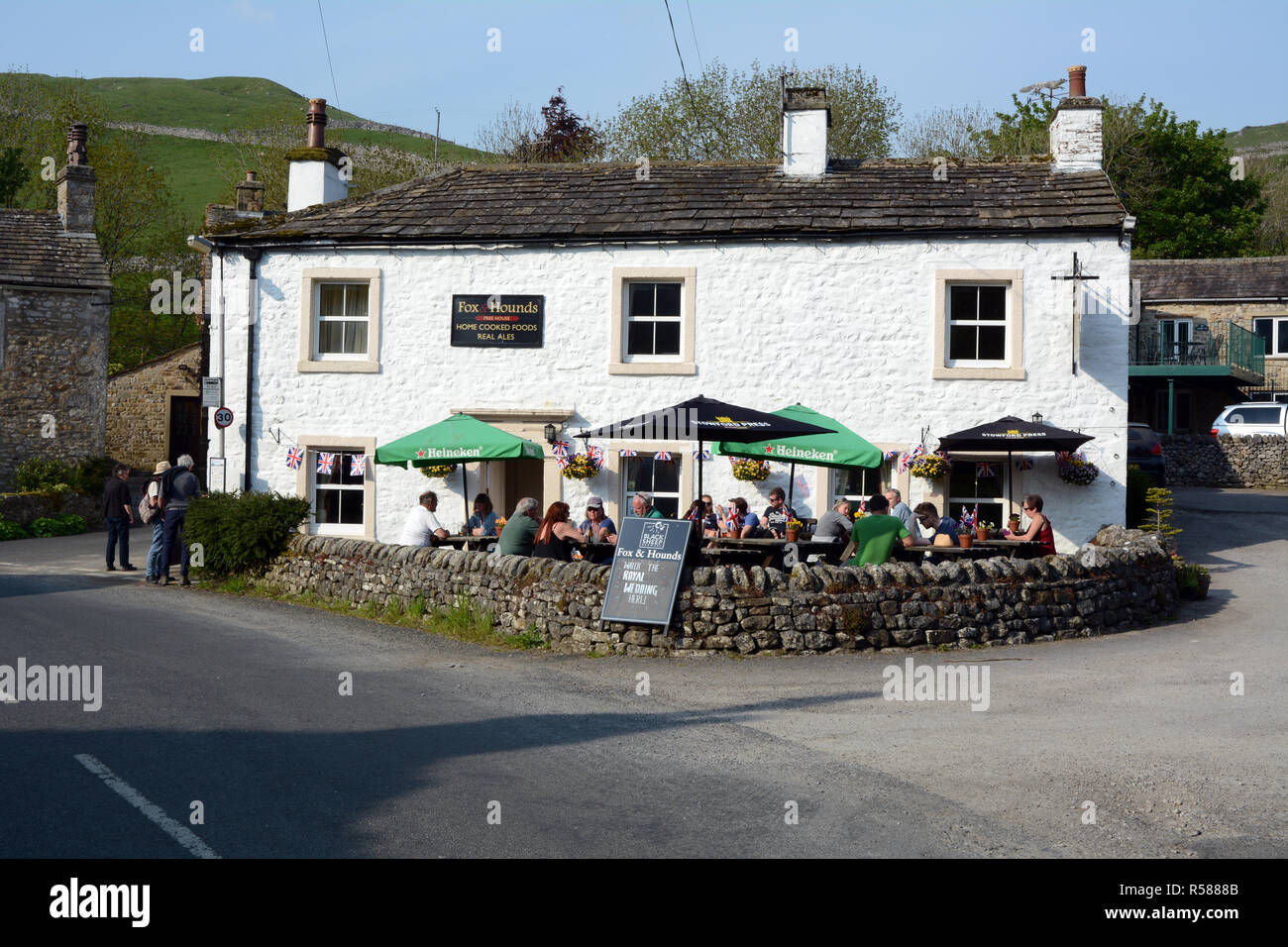 La gente seduta in un patio esterno al The Fox and Hounds Inn e il pub in Starbotton su Yorkshire Dales modo sentiero escursionistico, nell'Inghilterra del Nord, Regno Unito Foto Stock