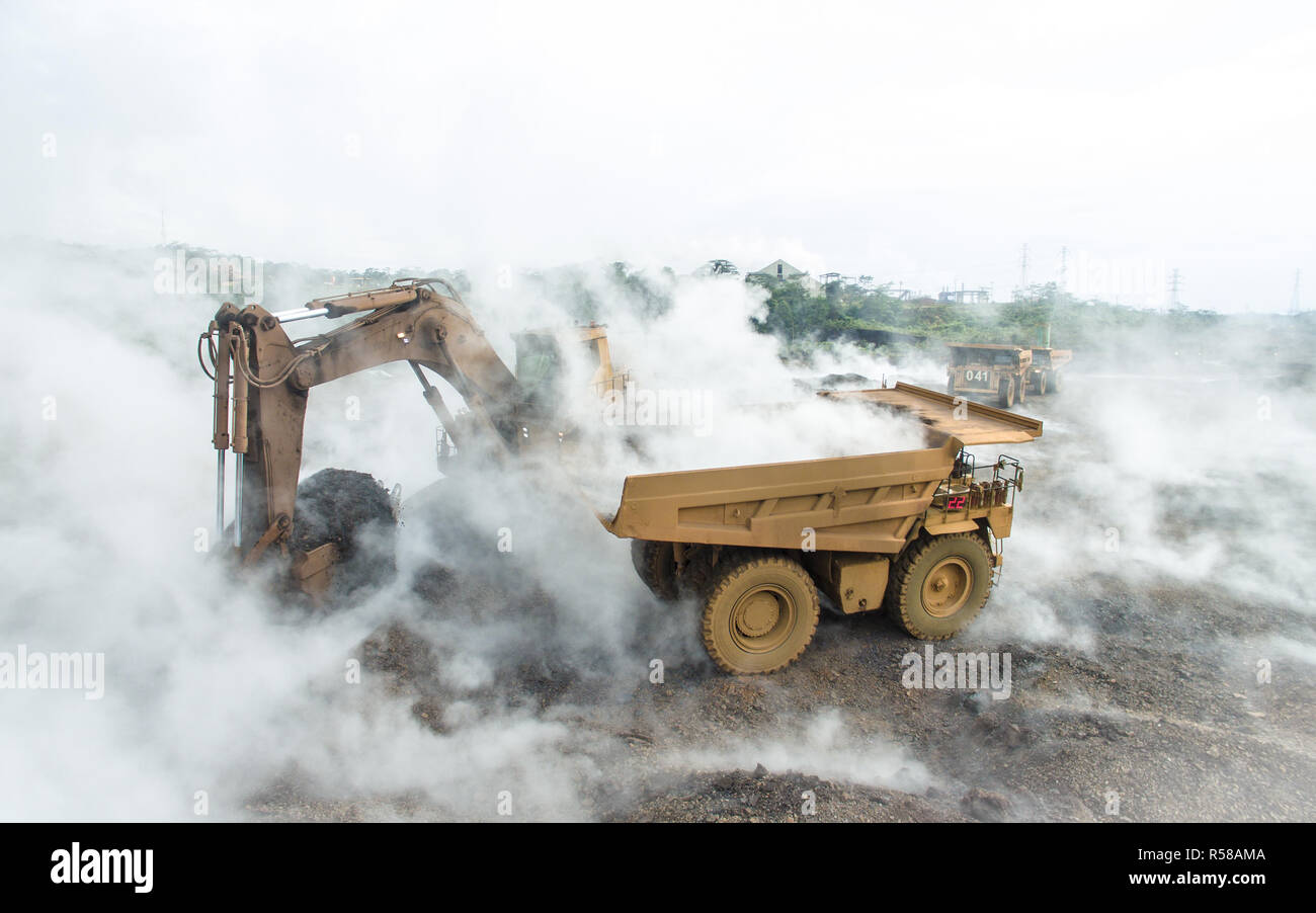 Caldo e smokey scoria materiale da caricare in un dump di data mining carrello, nelle miniere di nichel in Sud Sulawesi, Indonesia Foto Stock