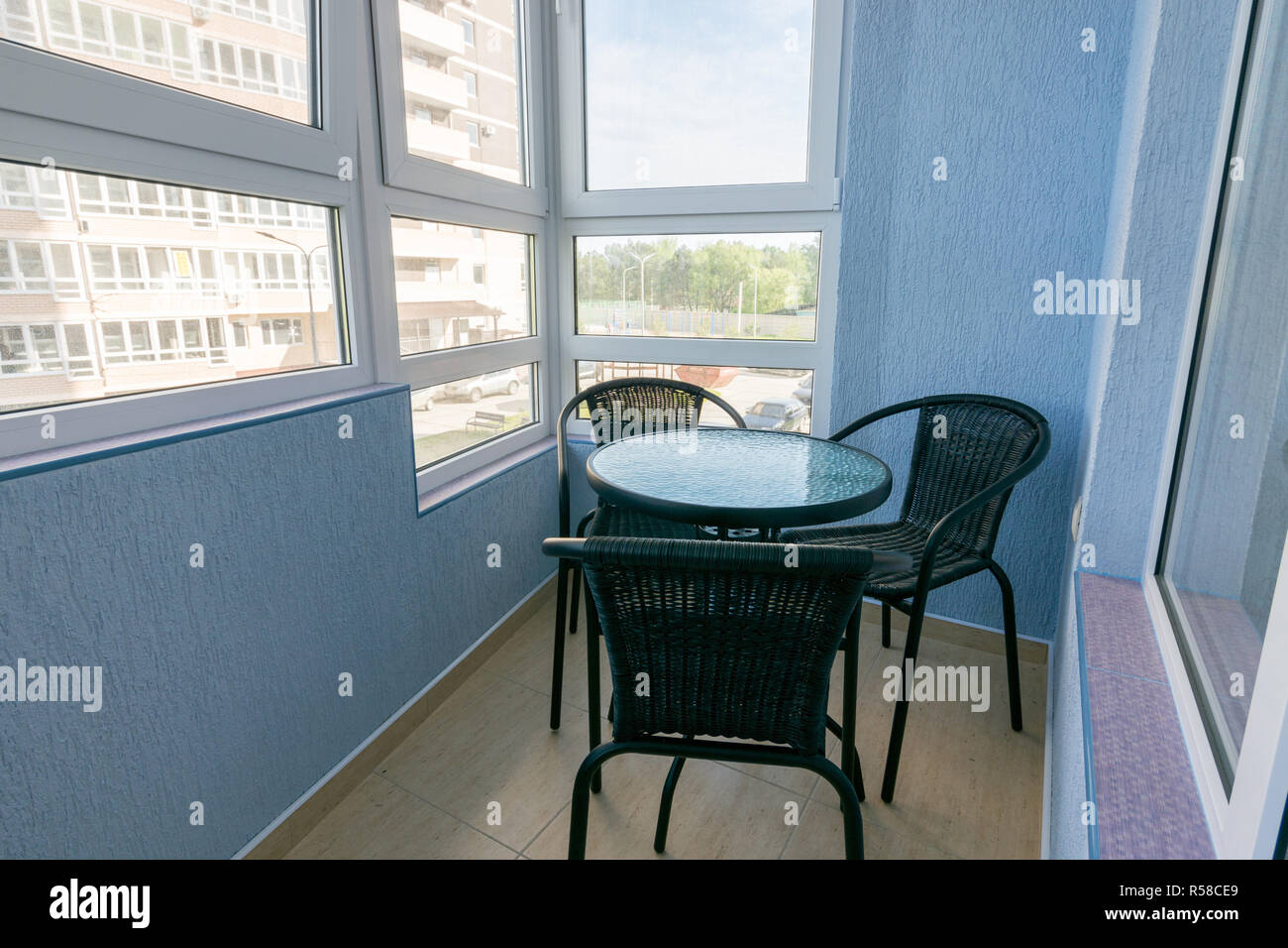 Un tavolo e tre sedie sul balcone dell'appartamento di un appartamento multistory building Foto Stock
