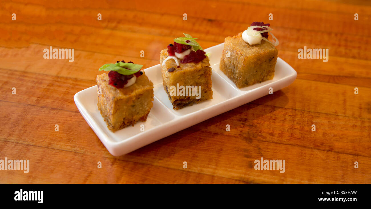 Stuzzicanti tapas di saporite patate e morsi di prosciutto con la barbabietola rossa assaporare e aioli in bianco, segmentato piatto sul tavolo di legno top Foto Stock