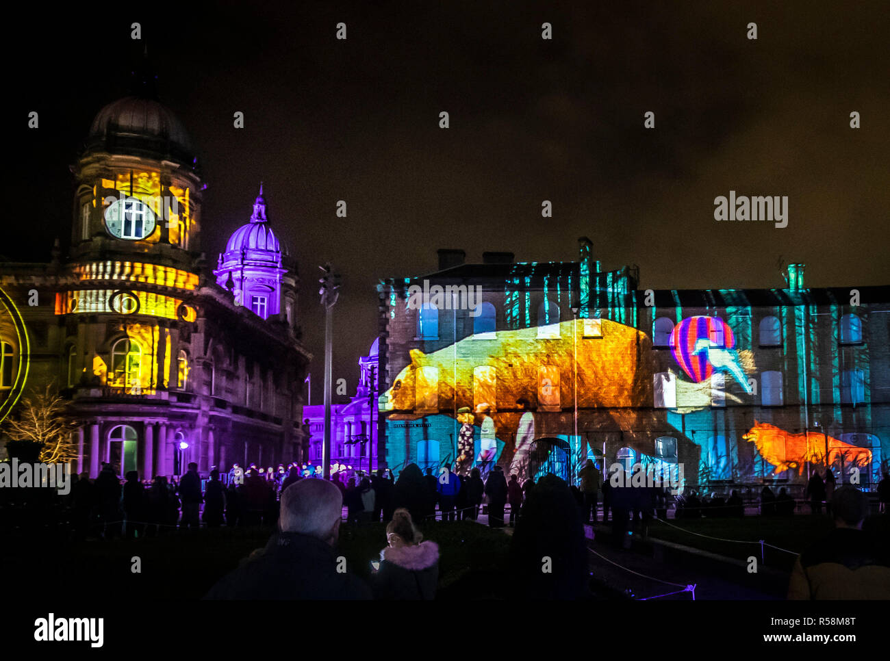 I membri del pubblico di un'opera intitolata Oh la notte!, un letto la storia di tempo che viene proiettato sul lato di un edificio e fa parte del festival delle arti di leggende urbane: Northern Lights attuale luogo di Hull. Foto Stock