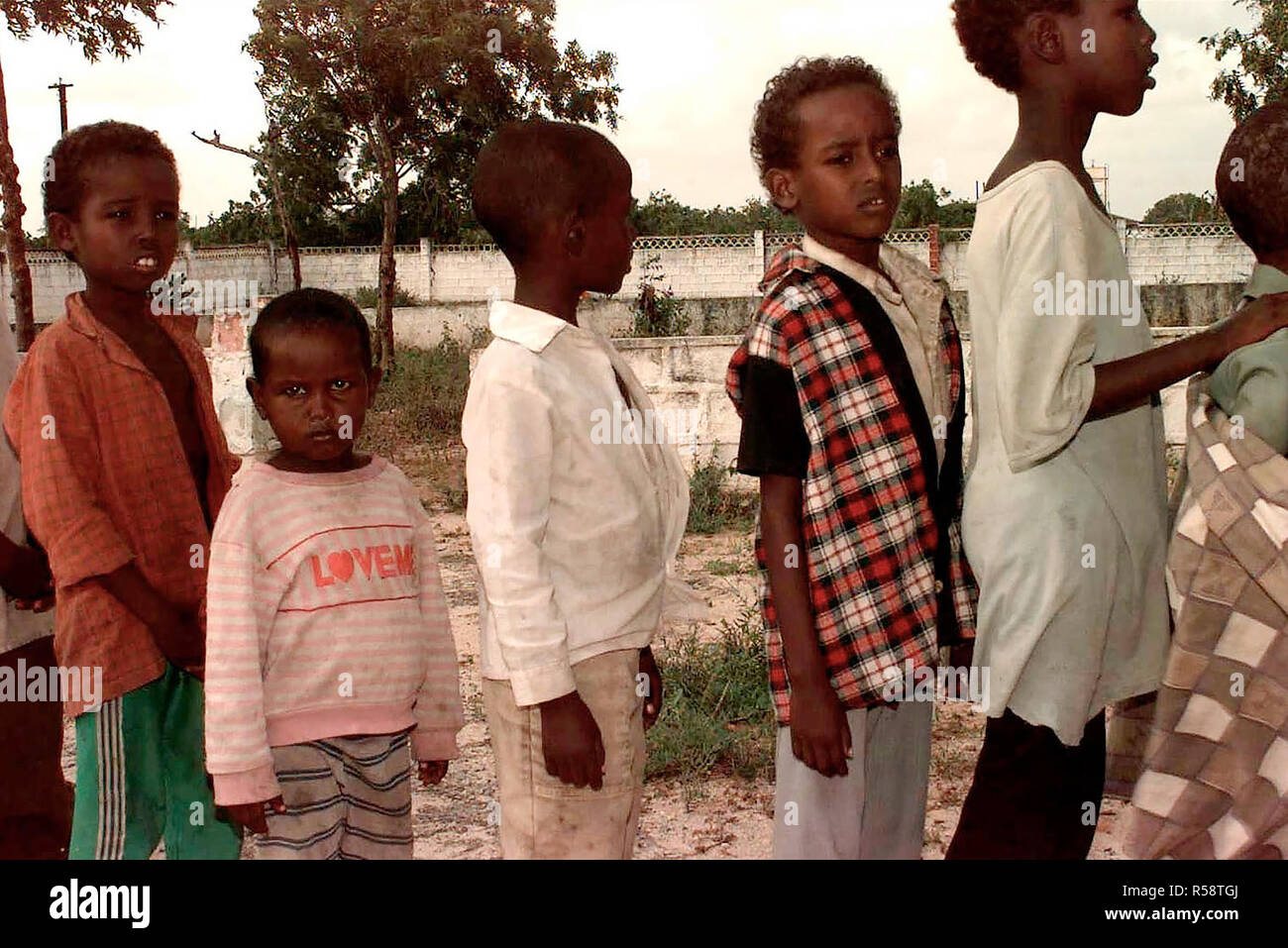 Sei ragazzi Somali attendere in linea pazientemente a un orfanotrofio dove US Navy personale medico (non mostrato) sono state fornendo controlli per i bambini. L'orfanotrofio è appena fuori di Mogadiscio. US Navy e Air Force il personale medico incontrato fino a un civile care group (non mostrata) per aiutare a dare il check-up per i bambini in orfanotrofio. Una volta ottenuto la parola che vi è stata una squadra medica in città, le donne dall'area locale ha iniziato a portare i loro bambini (non mostrato). Il team ha cercato di vedere come molti come possibile, ma fornisce rapidamente corse fuori. Questa missione è a diretto sostegno di Restore Hope Foto Stock