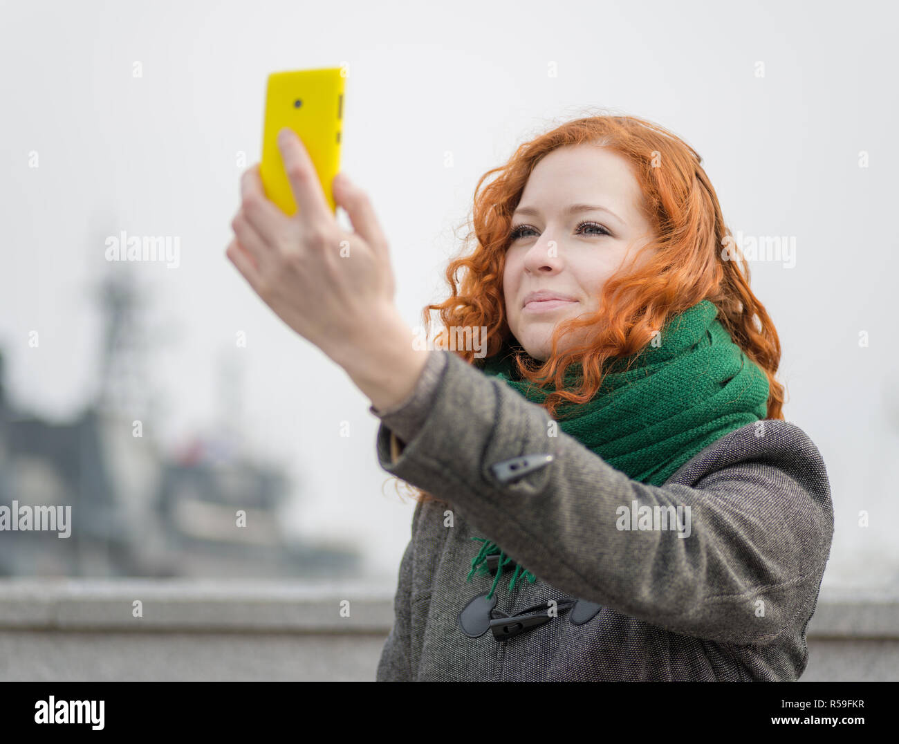 Giovane ragazza redhead prendendo un selfie all'esterno. Foto Stock