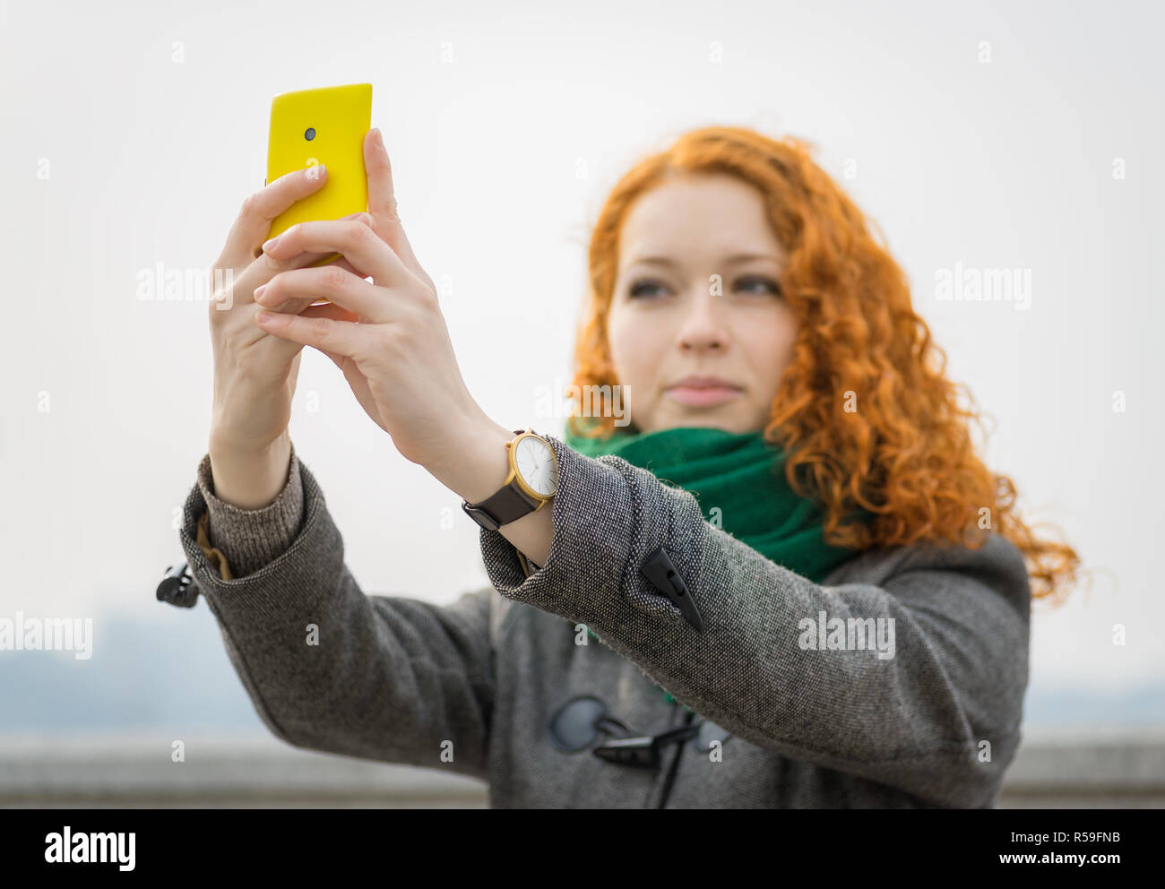 Giovane ragazza redhead prendendo un selfie all'esterno. Foto Stock