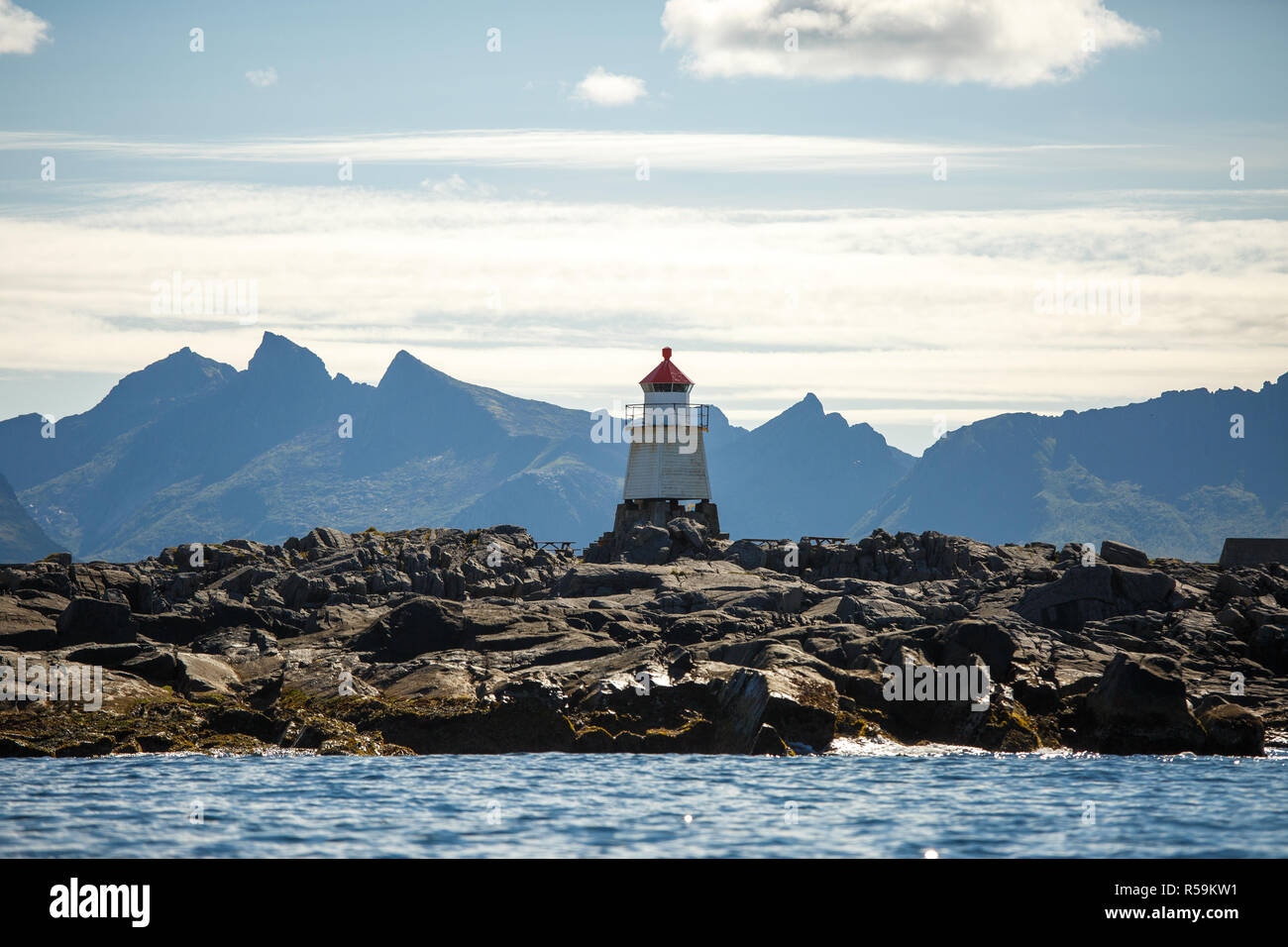 Foto del faro sul mare sullo sfondo di rocce e cielo molto nuvoloso Foto Stock