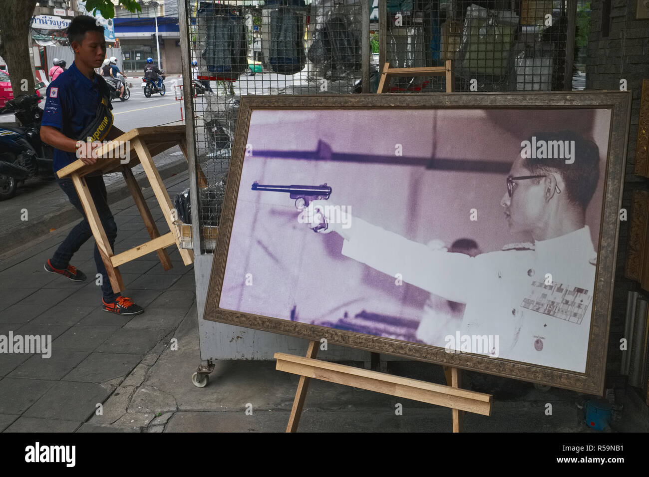 Un negozio situato nei pressi di numerosi negozi di pistola a Bangkok visualizza una rara foto di ex Re Tailandese Bhumipol Adulyadej, nella sua gioventù un appassionato di sport tiratore scelto Foto Stock