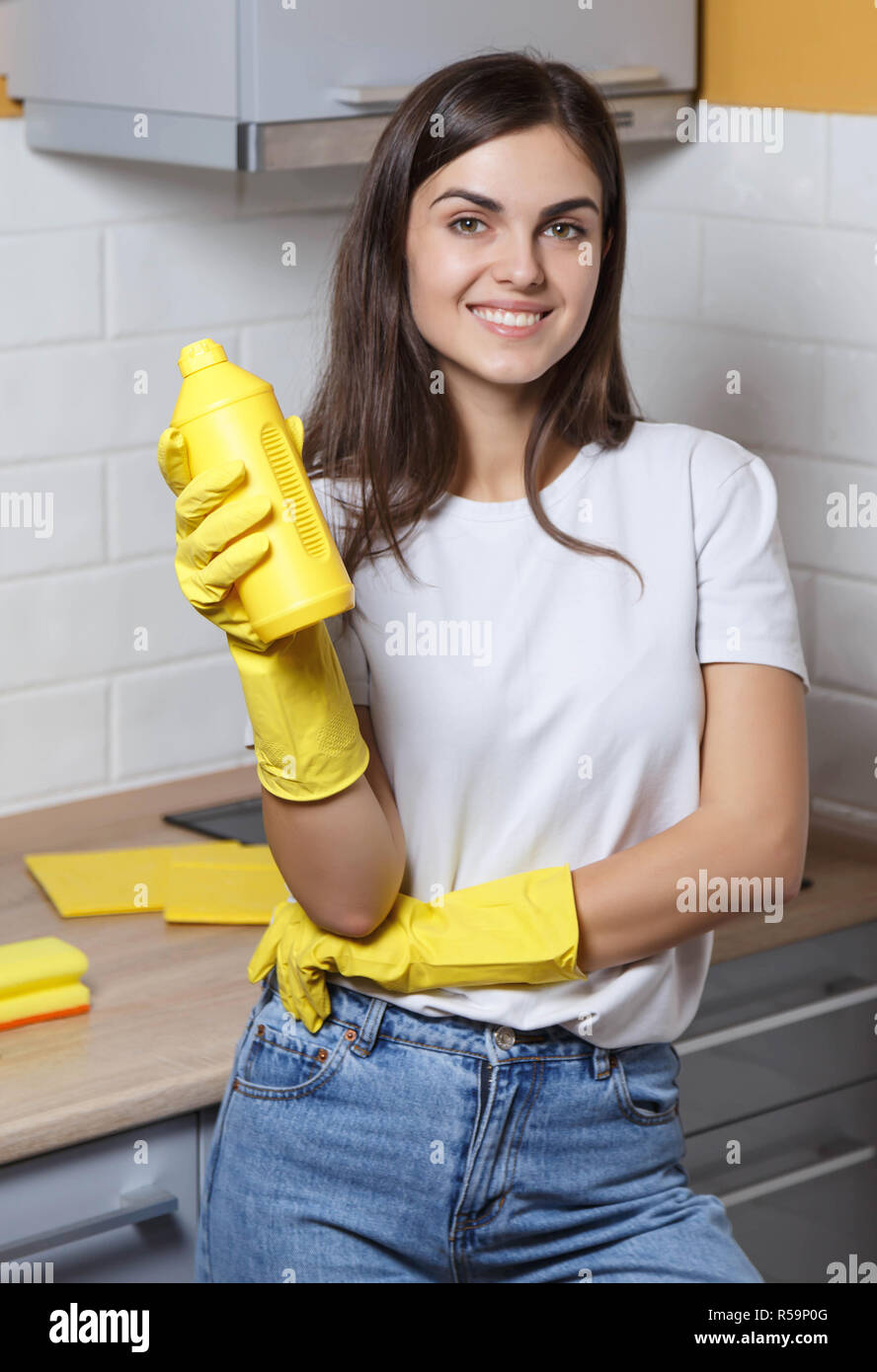 Felice Con I Capelli Lunghi Ragazza In T Shirt Bianco Giallo Da Indossare Guanti Di Gomma Sorridente E Bottiglia Di Contenimento Di Detersivo Durante La Pulizia Di Una Cucina Foto Stock Alamy