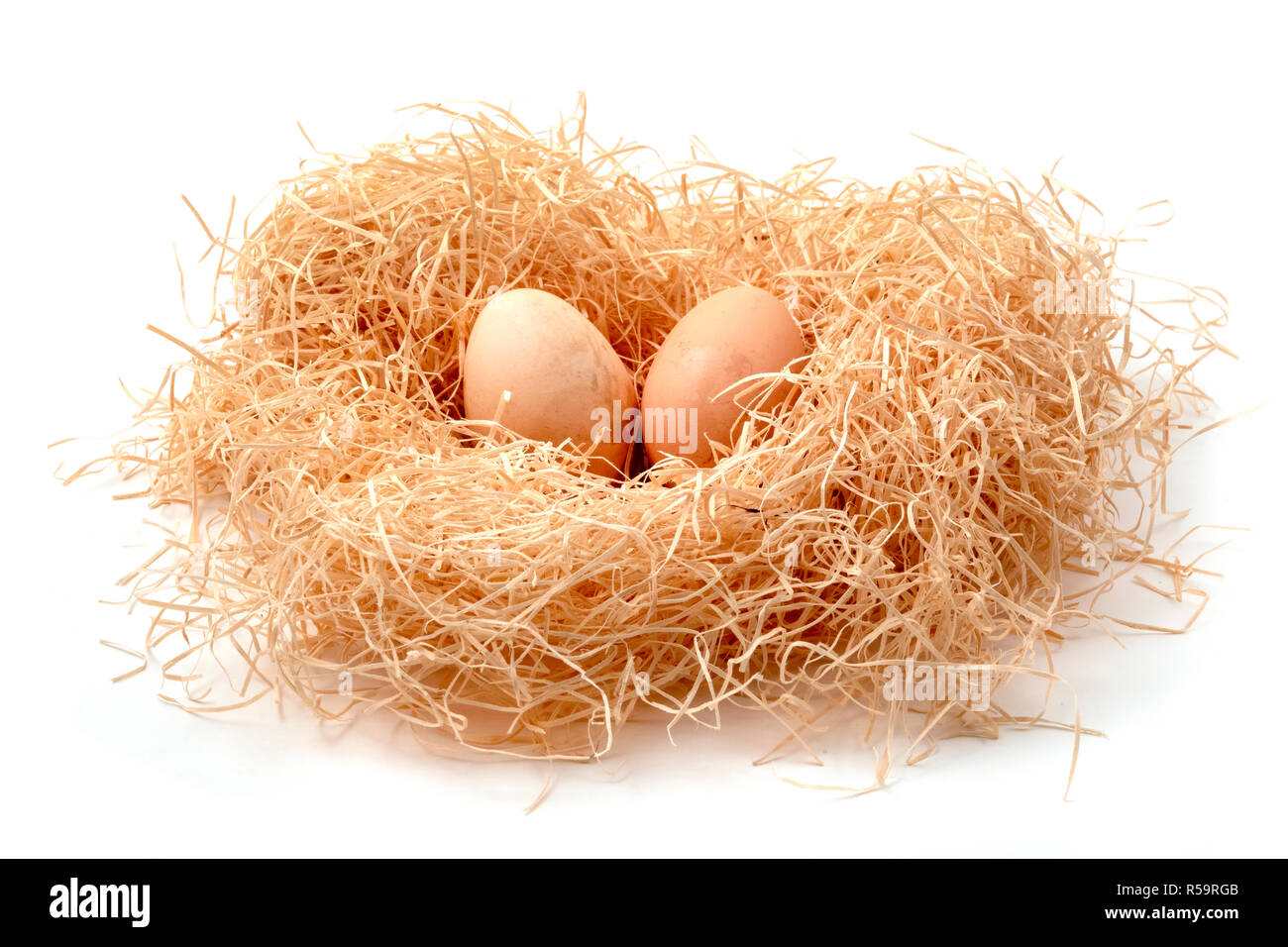 Le uova in un nido di paglia su sfondo bianco Foto Stock
