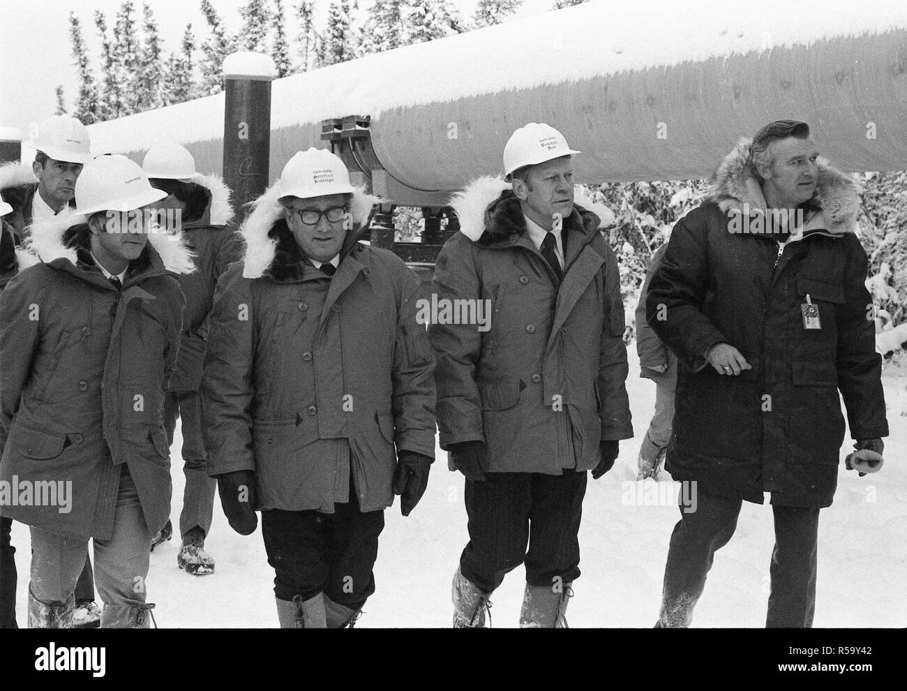 29 novembre 1975 - Alyeska Pipeline Service Company Stazione della pompa n. 8 - Fairbanks AK - Federal Energy Administration Amministratore Frank Zarb, Segretario di Stato Henry Kissinger e il Presidente Ford Touring la pipeline Trans-Alaska Indossare copricapi rigidi, arctic ingranaggio meteo Foto Stock