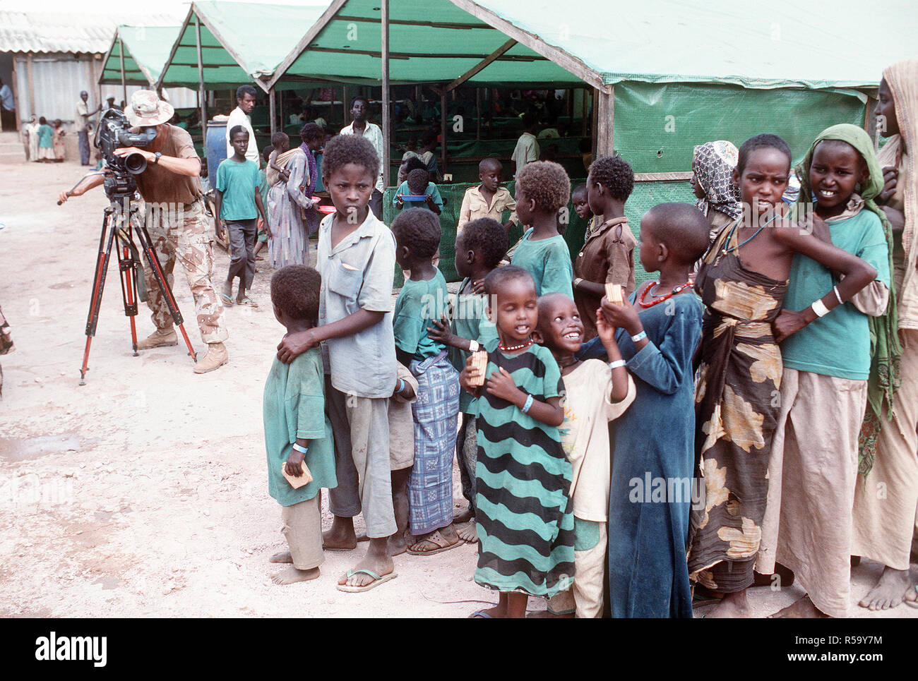 1993 - capo fotografo il compagno di Robert Sasek videotape somali allineando per un pasto presso la preoccupazione del centro di alimentazione durante la multinazionale soccorsi RESTORE HOPE. Il centro è gestito dagli irlandesi in rilievo la preoccupazione dell'organizzazione. Foto Stock