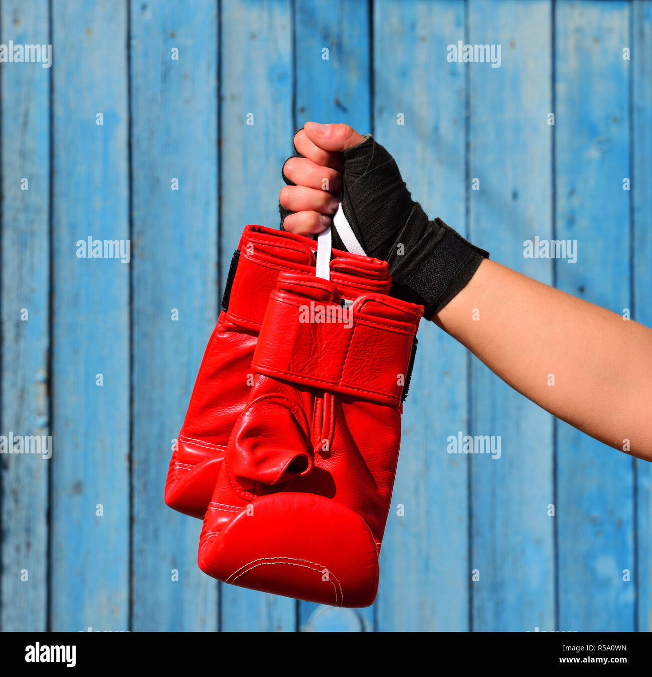 Red guantoni da pugilato appeso a una fune in una donna di lato Foto Stock