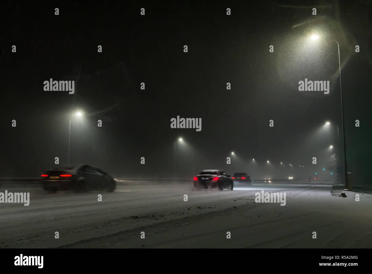 Vetture guida sulla strada di notte durante una nevicata di notte Foto Stock