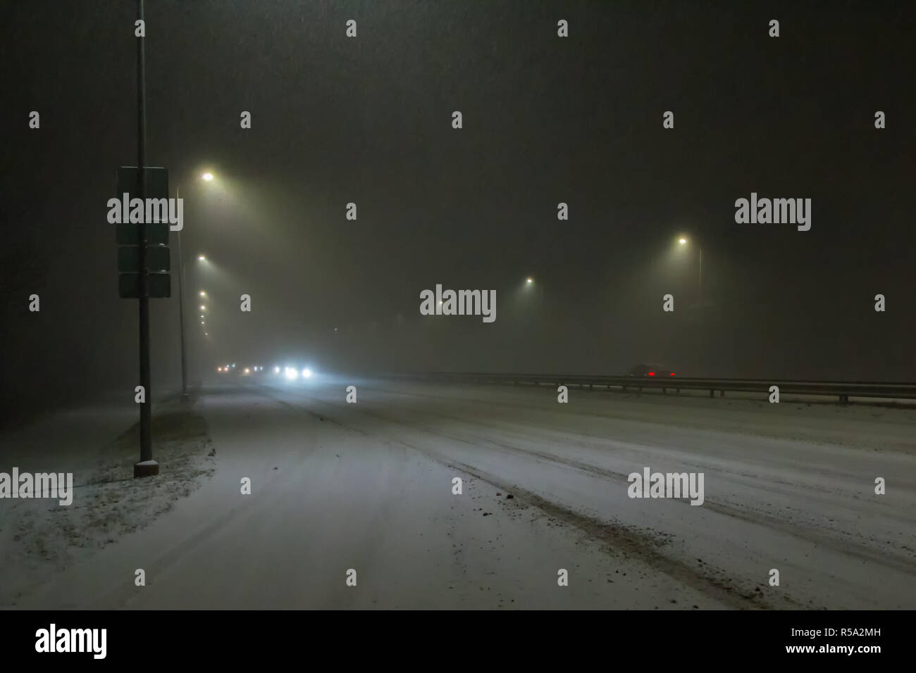Vetture guida sulla strada di notte durante una nevicata di notte Foto Stock