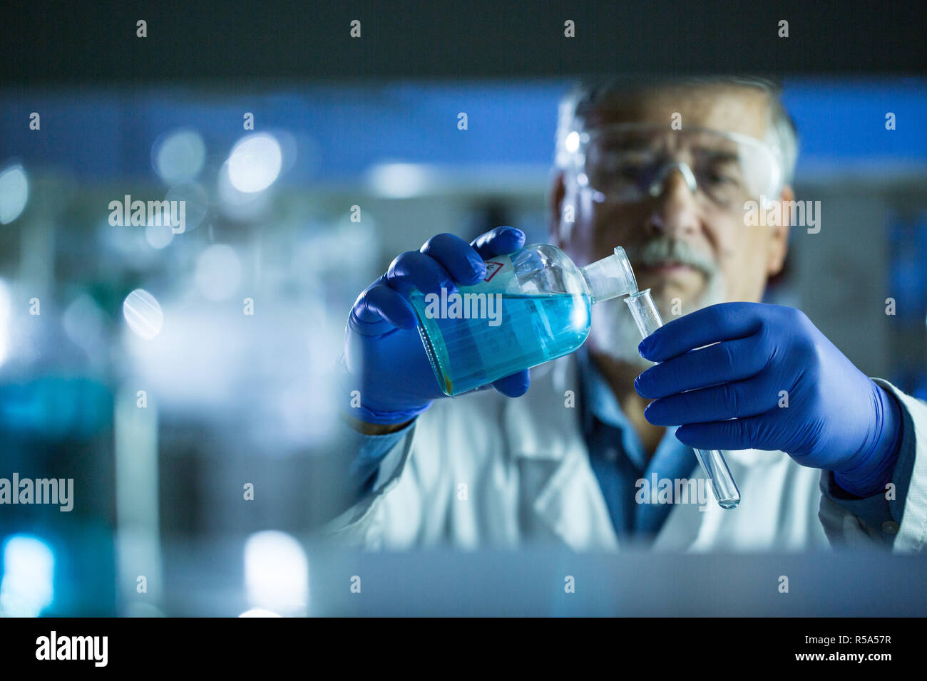 Maschio senior researcher di effettuare attività di ricerca scientifica in un laboratorio (SHALLOW DOF dai toni di colore immagine) Foto Stock