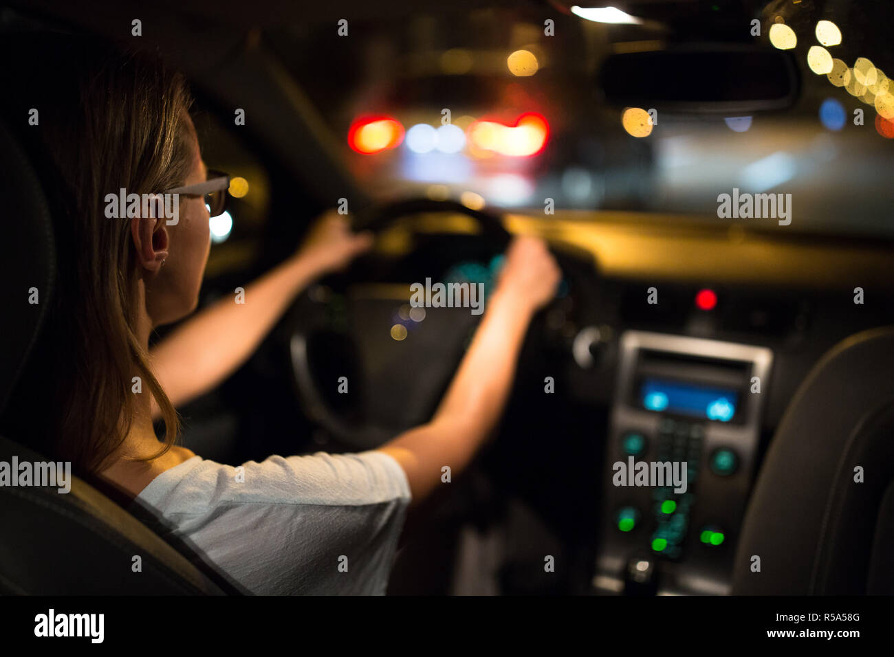 Unità femminile alla guida di una macchina di notte (SHALLOW DOF dai toni di colore immagine) Foto Stock