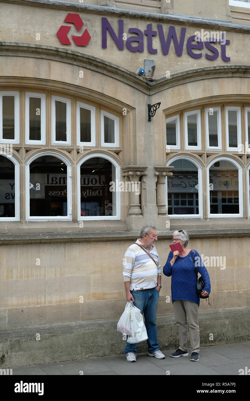 Una coppia di mezz'età parlando al di fuori di un high street bank in pozzetti, Somerset, Regno Unito. Foto Stock