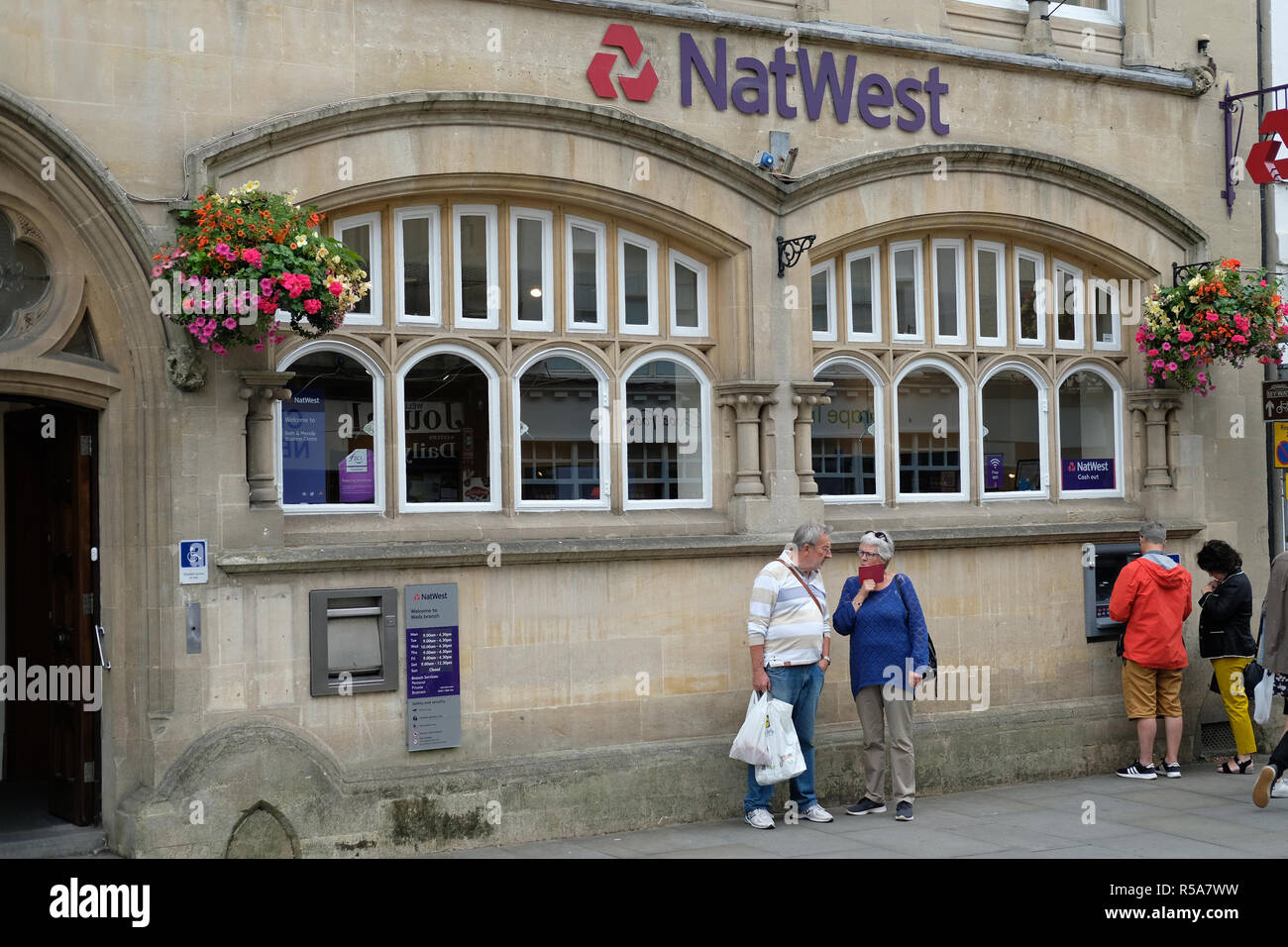 Una coppia di mezz'età parlando al di fuori di un high street bank in pozzetti, Somerset, Regno Unito. Foto Stock
